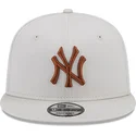 gorra-plana-beige-snapback-con-logo-marron-9fifty-league-essential-de-new-york-yankees-mlb-de-new-era